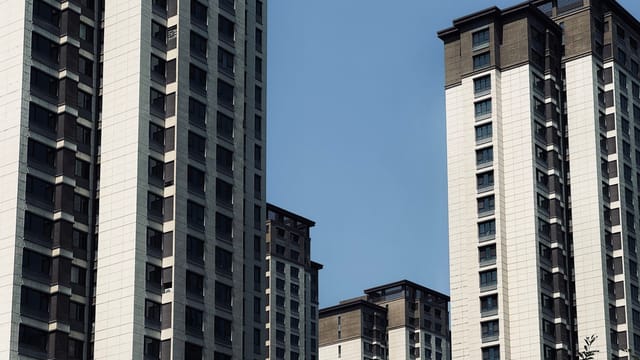 A cluster of modern high-rise buildings against a bright blue sky, showcasing urban architecture.