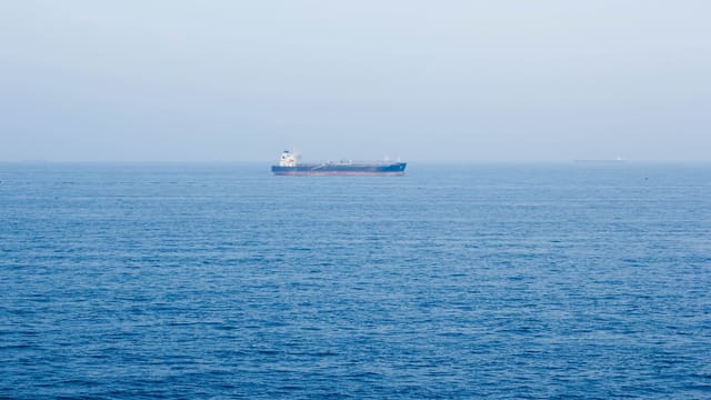 A large cargo ship sails on the tranquil ocean near Vũng Tàu, Vietnam, symbolizing global commerce.