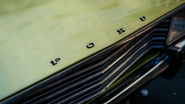 Detailed close-up of a vintage Ford car front with a focus on the hood and emblem.