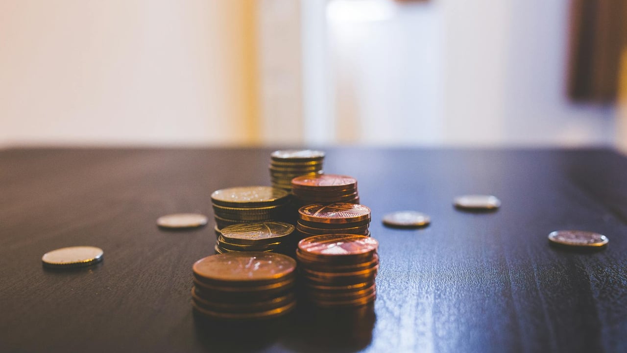 Close-up of various coins stacked on a dark table indoors.