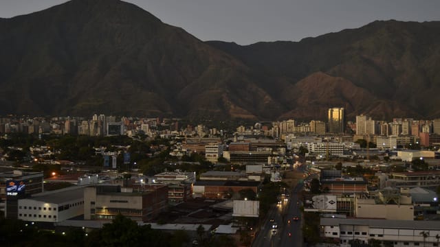 An aerial view of Caracas, Venezuela, showcasing cityscape with mountains at twilight.