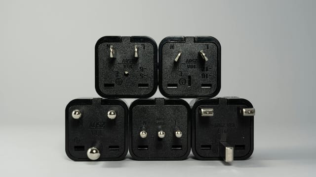 A collection of various black international power plug adapters for global electronics use.