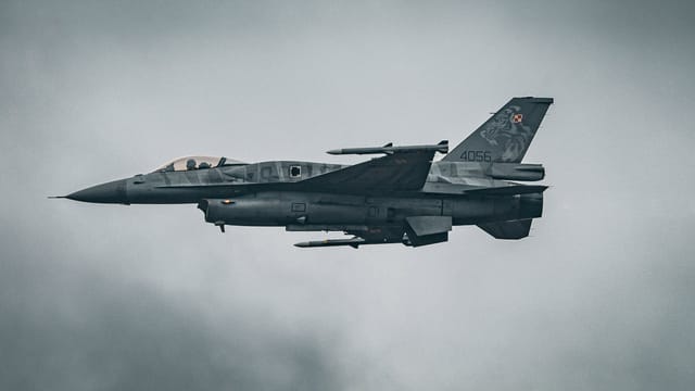A dynamic capture of an F-16 fighter jet soaring through the sky over Hechtel-Eksel.