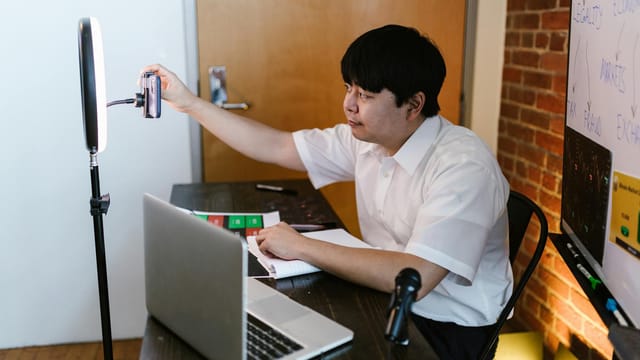 Vlogger recording content with a smartphone and ring light, showcasing an interactive workspace.