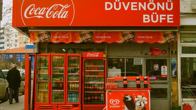 A vibrant Coca-Cola booth in Kayseri, Türkiye, showcasing beverages at a bustling street market.