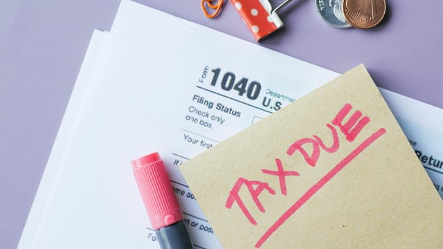 Close-up of IRS Form 1040 with 'Tax Due' note and stationery on a desk.