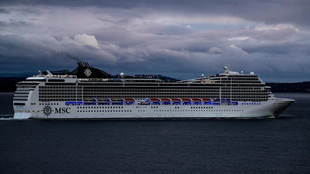 MSC cruise ship navigating waters near Hobart, Tasmania against a dramatic cloudy sky.