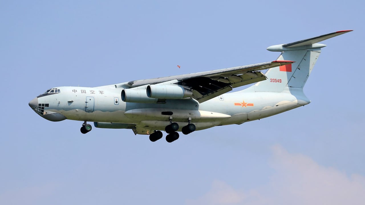Military cargo plane mid-flight against a clear blue sky, showcasing aviation technology.