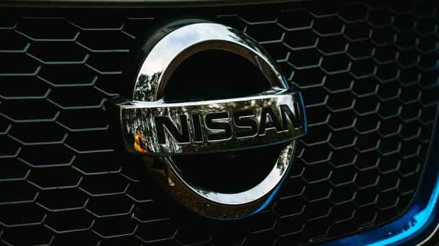 Detailed shot of the Nissan logo on a car grille grid, emphasizing automotive branding.