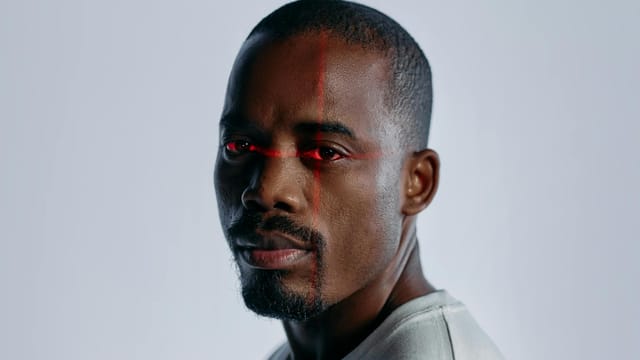 Close-up of a man with a futuristic laser scanning effect over his eyes, suggesting technology and identity themes.