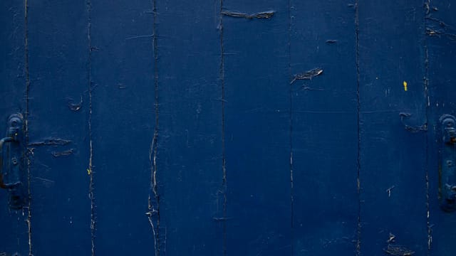 Detailed view of a weathered blue wooden surface in Paris, showcasing aged textures and patterns.