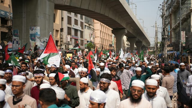 A large Pro-Palestinian protest with flag waving and banners, demonstrating solidarity in Dhaka, Bangladesh.
