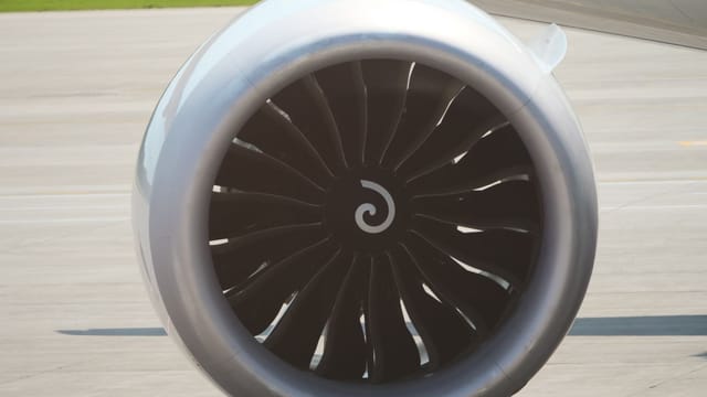 Detailed view of a modern airplane jet engine on an airport tarmac.