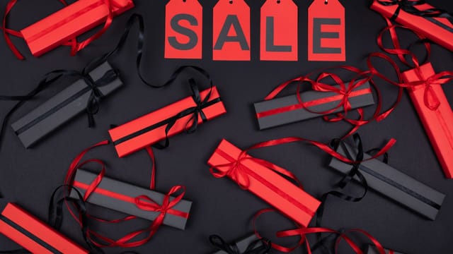 Red and black gift boxes with sale tags on black background, perfect for promotions.