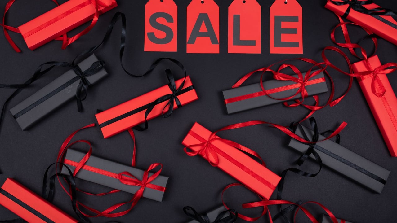 Red and black gift boxes with sale tags on black background, perfect for promotions.