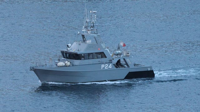 Military patrol boat cruising through ocean waters.
