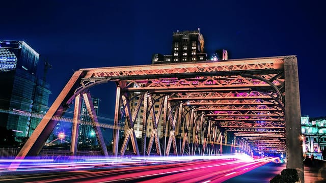 Vibrant long-exposure shot of light trails on Shanghai's iconic bridge at night.