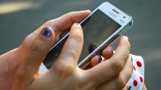 A woman interacts with a smartphone outdoors, focusing on connectivity and technology.