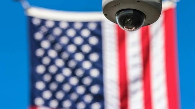 Surveillance camera focusing on security with American flag backdrop.