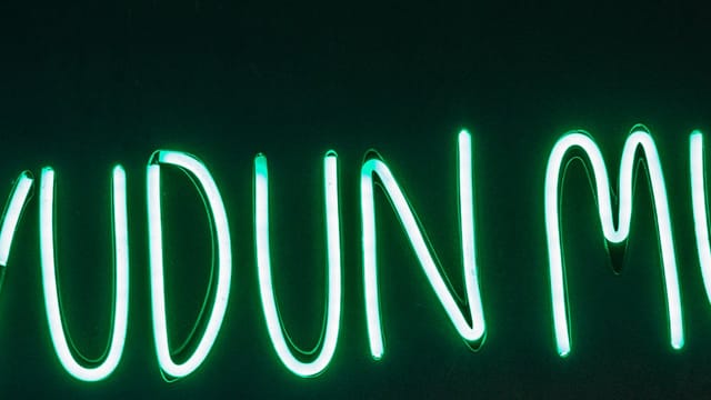Vibrant neon sign 'Uyudun Mu?' glowing against a black background in Istanbul, Turkey.