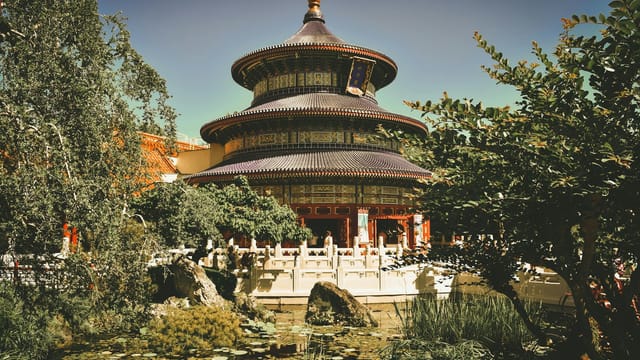 A stunning pagoda amidst a vibrant garden with a reflection in the pond, capturing cultural essence.