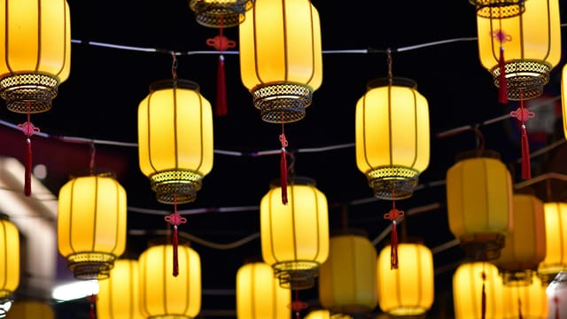 Elegant yellow lanterns glowing warmly against the night sky in Dalian, China.