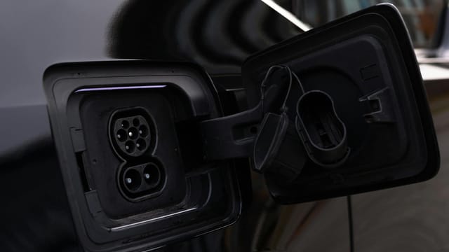 Close-up image of an electric vehicle charging port on a black car.