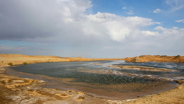 Beautiful wetland landscape in Qom, Iran with sunlit sky and serene waters.