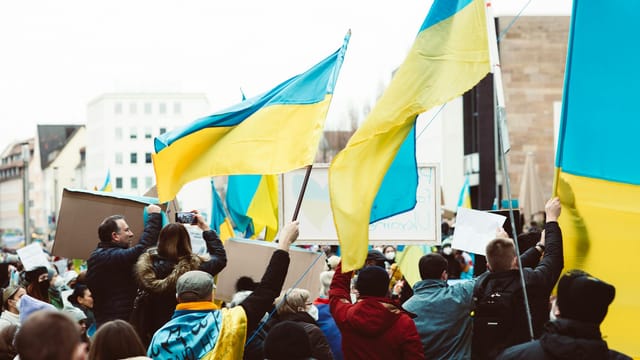 Crowd holding Ukrainian flags during a peaceful protest in urban setting.