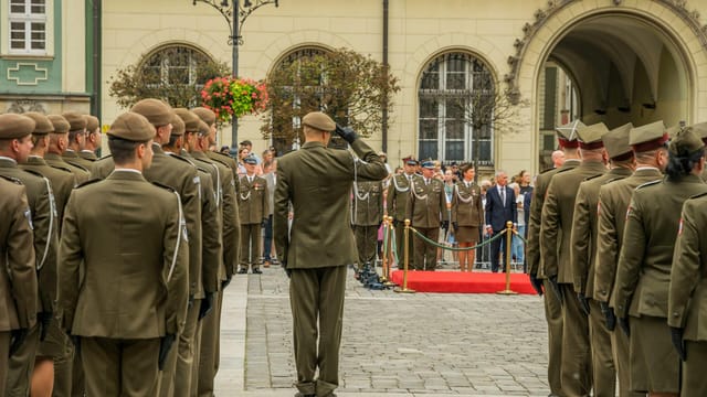 A formal military ceremony featuring Polish soldiers in uniform in Wrocław's historic square.
