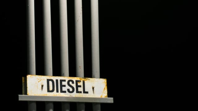 Diesel fuel sign on metal pipes against a dark black background at night.