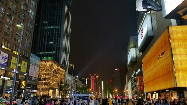 Bustling urban scene in Chengdu's shopping district with vibrant lights and crowds at night.