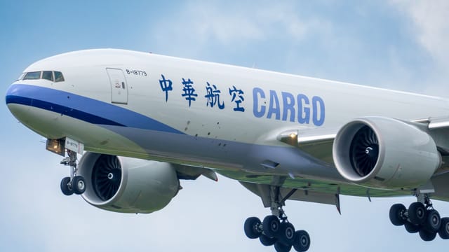 A large cargo airplane approaches landing under a clear sky.