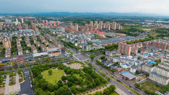 Aerial view of Luoshan County's urban landscape with green parks and high-rise buildings.