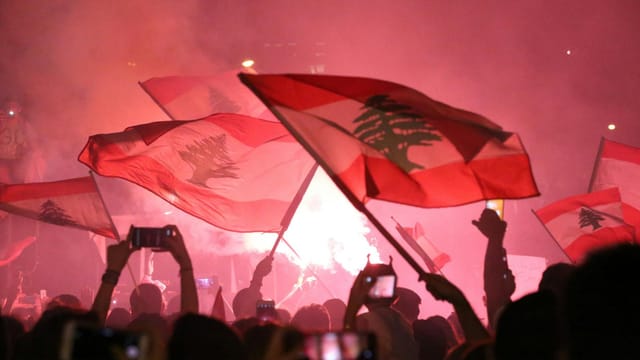 Vibrant night festival in Beirut with people waving Lebanese flags, capturing a moment of unity.