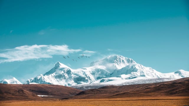 Breathtaking view of snow-capped mountains under a clear blue sky in Tibet.