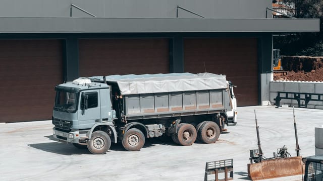A large dump truck parked at an industrial construction site near a building.