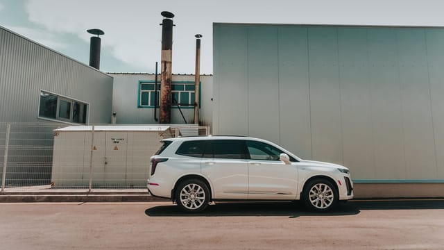A sleek white SUV parked beside an industrial building in Almaty, Kazakhstan.