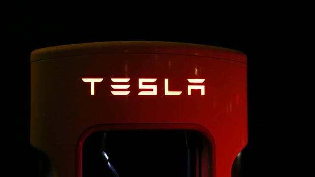 Close-up of a Tesla charging station illuminated at night, showcasing modern automotive technology.