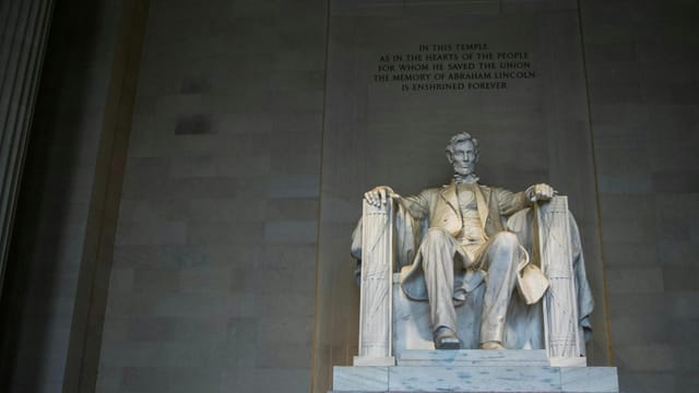 From below of marble statue of American president sitting on chair near wall with inscription located in Washington DC