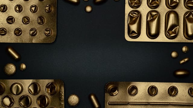 Close-up of metallic pills and blister packs on a dark surface, showcasing healthcare themes.