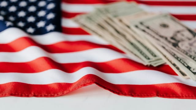 Close-up of American flag with US dollar bills symbolizing economy and patriotism.