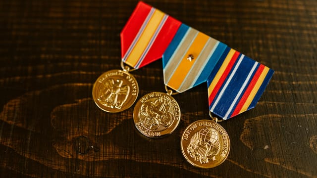 Close-up of gold military medals with ribbons on a wooden table.