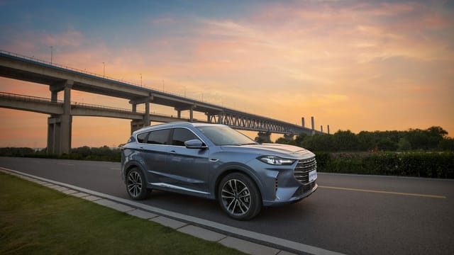 Modern SUV driving on a highway during sunset, showcasing elegance and luxury.