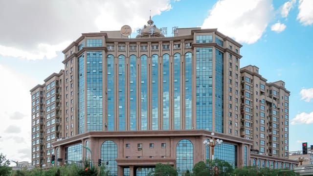 A grand, multi-story hotel building with modern architecture against a clear blue sky.
