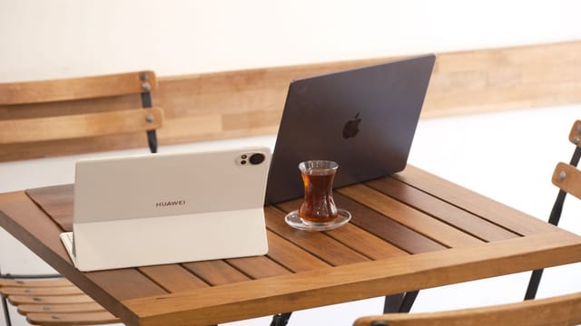 Two tablets and a Turkish tea on a wooden table create a cozy workspace in a café in İzmir.
