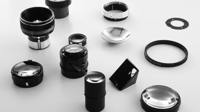 A collection of black and white camera lens components arranged on a surface, showcasing photography equipment details.