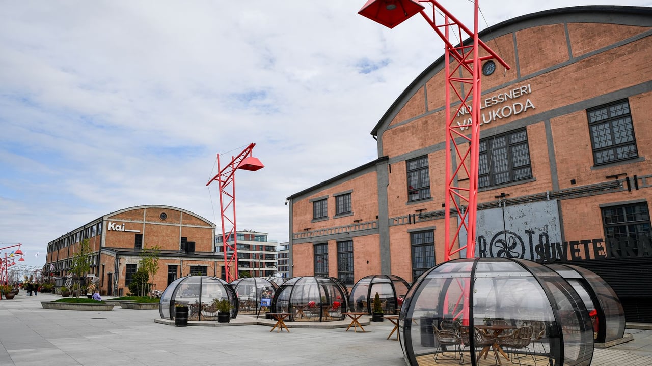 Outdoor dining pods and industrial architecture create a unique urban atmosphere in Tallinn, Estonia.