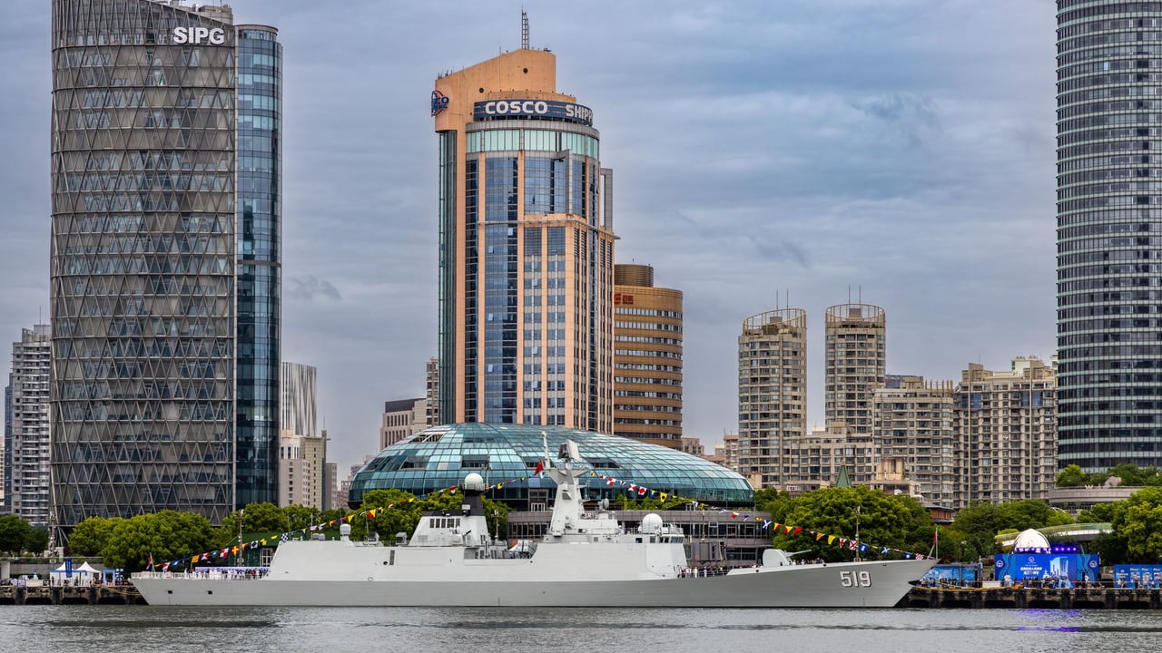 Contemporary skyline of Shanghai with a naval ship anchored, capturing urban architecture and maritime activity.