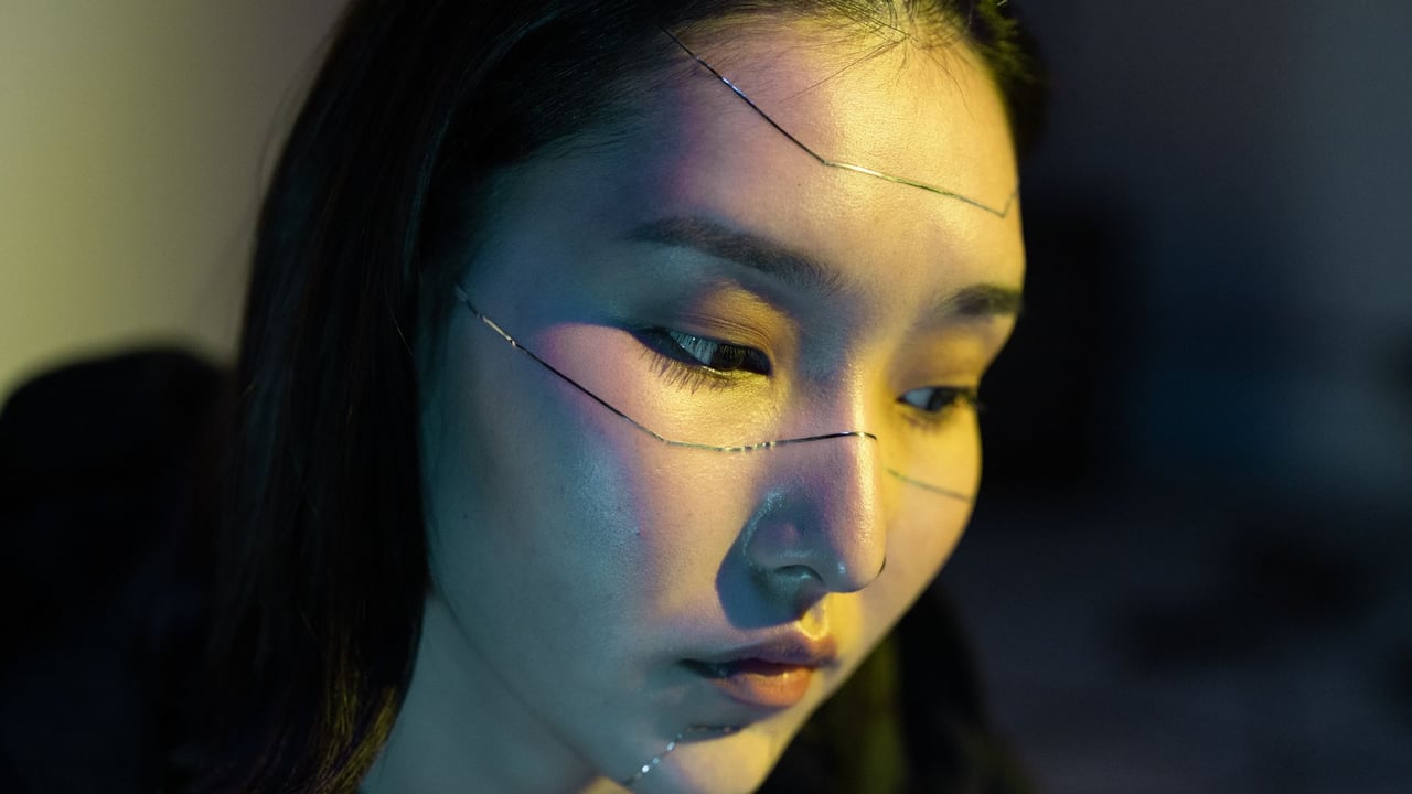 Close-up of an Asian woman in a cyberpunk-themed portrait with face stickers.